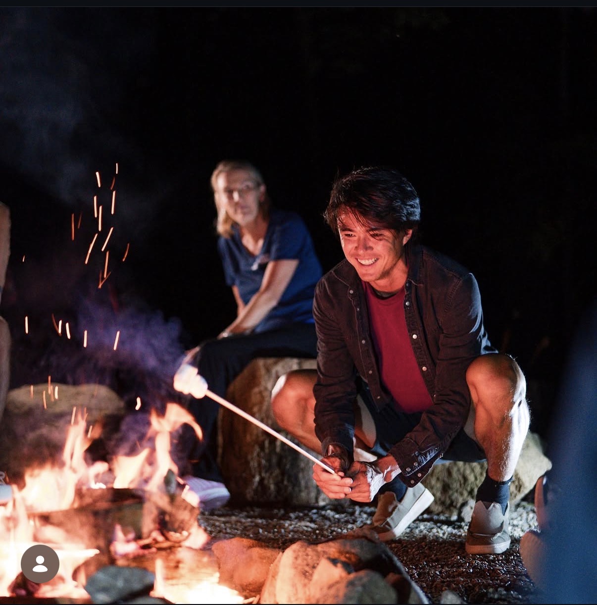 Participant roasting marshmallow at Alpine fire pit